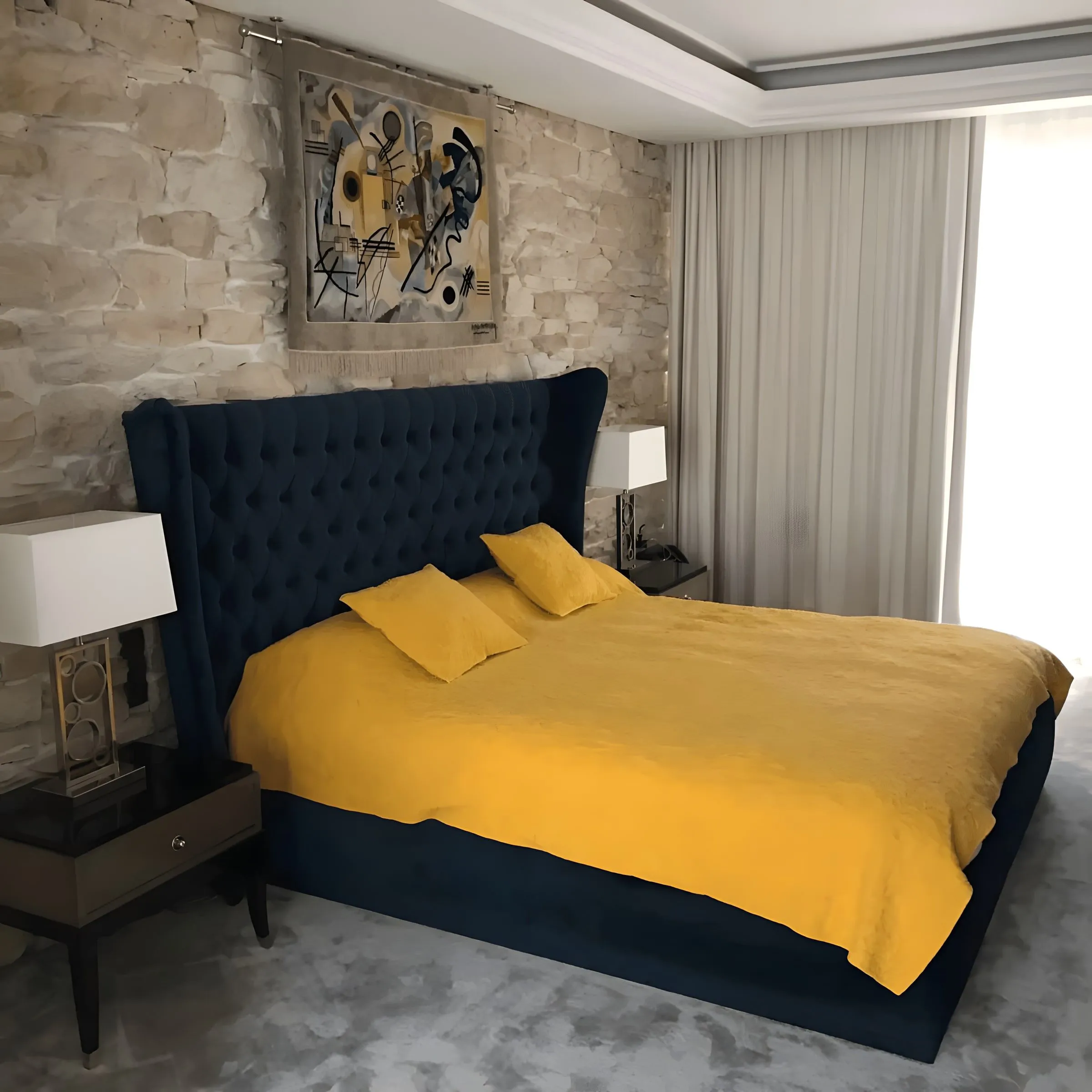 Dormitorio con cabecero tapizado y pared de piedra